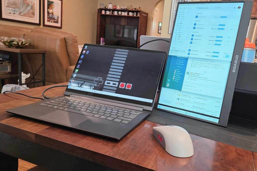 A laptop on a table with a small monitor screen next to it in portrait orientation.